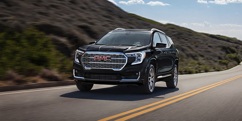 A black GMC Terrain driving on a road.